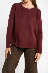 Sweater de tejido de punto color bordó, con cuello redondo, mangas largas y puños acanalados. Presenta un diseño de corte recto y textura suave.