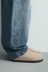 Zueco de piel con acabado serraje color beige, con plantilla anatómica, horma redonda y suela de volumen negra.