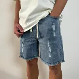 Bermuda de jean estilo jogger con efecto desgastado, roturas frontales y ruedo desflecado.