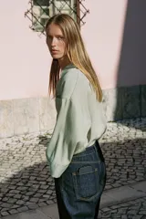 Camisa de corte oversize color marrón, con cuello solapa, mangas anchas por debajo del codo y bolsillo delantero de plastrón. Cierre frontal con botones.