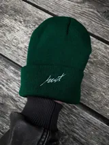 Gorro de lana verde oscuro con dobladillo y bordado blanco con la palabra "Just".