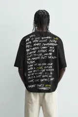 Camiseta negra de corte boxy fit, cuello redondo y manga corta, con estampado frontal en blanco y amarillo que dice "Social Media & Ciao Amore".