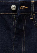 Falda corta de jean en color azul oscuro, con diseño entallado, cinco bolsillos, trabillas para cinturón y una abertura frontal en el bajo.
