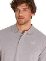 Remera tipo polo de manga corta color gris melange, con cuello de punto acanalado y tapeta con botones. Presenta el logo de CAT estampado en el pecho y un pequeño detalle bordado en color amarillo en la manga.