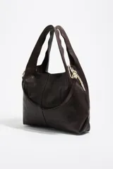 Bolso de mano grande de estructura blanda confeccionado en piel vacuna color marrón oscuro. Presenta asas fijas, cierre de cordón ajustable en los laterales y logo metálico de la marca en la parte frontal.