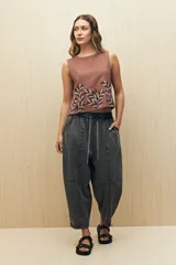 Pantalón de algodón color gris oscuro, estilo baggy o ancho, con cintura elástica y cordón ajustable. Presenta costuras marcadas que definen paneles en la pierna y puños ajustados en el tobillo.