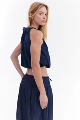 Blusa crop balloon de denim ultra liviano en color azul, con diseño sin mangas, cuello redondo y detalle de lazo para atar en la espalda.