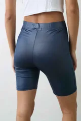 Calza corta tipo biker de tiro alto, confeccionada en tela engomada de acabado brillante con cintura elástica.