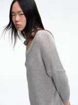 Sweater de punto con brillo, de corte relajado y escote en V. Presenta hombros caídos y mangas largas con puños acanalados.