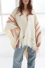 Ruana artesanal color crudo con rayas horizontales color ladrillo y flecos.