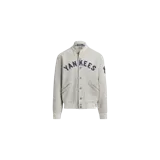 Campera tipo college de Polo Ralph Lauren en color gris melange, con cierre frontal de botones a presión, bolsillos ribeteados y cuello, puños y dobladillo de canalé. Cuenta con el nombre "Yankees" bordado en azul marino en el pecho y detalles distintivos de la marca.