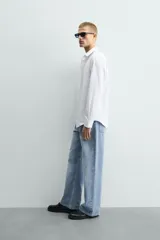 Camisa de corte slim fit confeccionada en tejido de algodón con textura. Presenta cuello italiano, manga larga con puños abotonados y cierre frontal de botones.