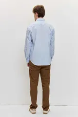 Camisa celeste de manga larga con cierre frontal de botones y cuello clásico.