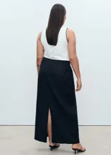 Falda larga de lino color negro, tiro medio, diseño estilo lápiz con abertura en la parte posterior y cierre de cremallera lateral.