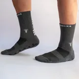 Medias deportivas de caña media color fucsia, con suela antideslizante de puntos negros y logo de la marca estampado en la parte superior.