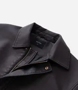 Campera de estilo urbano confeccionada en poliuretano con acabado lavado y textura que imita el cuero. Presenta cuello inglés, cierre frontal con cremallera, vista con botones y bolsillos delanteros amplios.