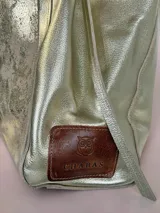Bolso tipo tote Chabas confeccionado en cuero genuino color plateado, con un bolsillo frontal texturizado en tonos metalizados y doble asa superior para el hombro.