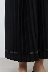 Vestido largo negro plisado con cuello halter y cinturón plateado.