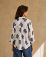 Camisa blanca de manga larga con estampado azul en contraste, cuello camisero y cierre frontal con botones.