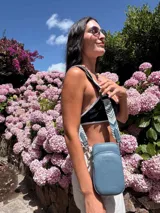 Bandolera compacta color rojo con textura de cuero, correa regulable y desmontable con diseño de rayas rojas y blancas. Cuenta con bolsillos frontales y cierre, interior forrado en tela.