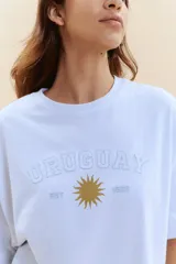 Remera de manga corta color celeste con estampa frontal que incluye la palabra Uruguay en tipografía universitaria, un sol y la inscripción 1825.