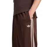 Pantalón deportivo Adidas modelo Firebird OS, color marrón con las clásicas tres tiras blancas a los lados y el logo del trifolio bordado. Cuenta con cintura elástica con cordón ajustable y diseño de corte recto y holgado.
