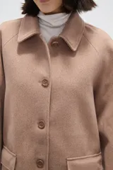 Tapado de paño color gris, con cuello camisero, cierre frontal de botones y bolsillos laterales con solapa.