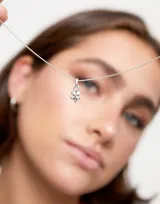 Dije plateado con forma de trébol de cuatro hojas.