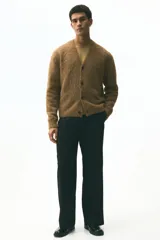 Cárdigan de punto marrón con textura peluda, cuello en V pronunciado y cierre frontal de botones. Presenta remates acanalados en puños y bajo, con un corte holgado.