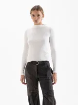 Polera blanca de tejido acanalado, con cuello alto y mangas largas ajustadas.