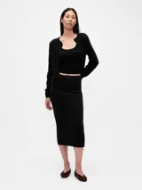 Saco de punto fino color marfil, con cuello redondo, cierre frontal con botones y mangas largas.