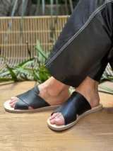 Sandalias chatas de cuero negro con tiras cruzadas.