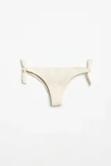 Bombacha de bikini tipo vedetina color beige, con textura arrugada y lazos laterales ajustables.