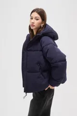 Campera puffer de color marrón oscuro, con diseño capitoneado, cierre frontal, capucha ajustable y bolsillos laterales con cierre.
