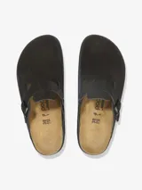 Sandalias cerradas de gamuza negra con plantilla anatómica de corcho-látex y suela de goma con plataforma. Presentan una tira ancha ajustable con hebilla metálica.