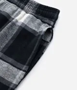 Pantalón de pijama de corte recto confeccionado en franela de algodón con estampado de cuadros en tonos blanco y negro. Presenta cintura elástica con cordón de ajuste para mayor comodidad.