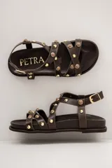 Sandalias de cuero color beige, con tiras cruzadas en el empeine decoradas con tachas y esferas doradas, base anatómica y pulsera ajustable al tobillo.