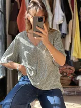 Blusa verde con estampado de pequeñas flores blancas y rojas, escote en V y mangas cortas holgadas.