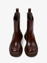 Botín Chelsea de cuero color marrón chocolate, con elásticos laterales y tirador trasero. Plataforma con suela de goma con diseño acanalado.