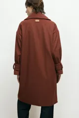 Abrigo de paño de lana con cuello alto estructurado, cierre frontal y mangas largas con detalle de botón en el puño.