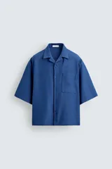 Camisa de corte boxy fit confeccionada en tejido con mezcla de lino. Presenta cuello bowling, manga corta, bolsillo plastrón en el pecho y cierre frontal con botones.