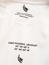 Remera oversize de algodón blanca con estampado frontal de coordenadas y texto "Cabo Polonio, Uruguay" en color marrón.