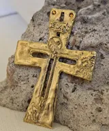 Colgante con forma de cruz de bronce con detalles grabados.