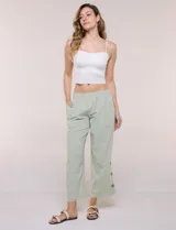 Pantalón de algodón rústico color verde, de tiro medio-alto con pretina elastizada y bolsillos laterales. Presenta corte holgado, diseño cropped de pierna ancha y aberturas laterales en los tobillos con detalles de botones.