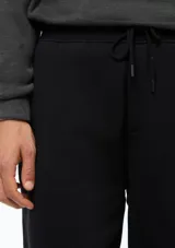 Pantalón tipo babucha de color azul oscuro, confeccionado con interior de felpa. Presenta cintura elástica con cordón de ajuste y puños acanalados en los tobillos.