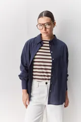 Camisa celeste de corte oversize, con mangas largas, cuello camisero y cierre frontal de botones.