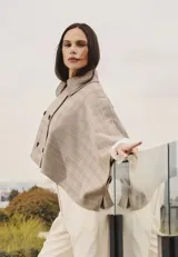 Capa estructurada con diseño de doble botonadura frontal y cuello camisero, confeccionada en tejido con estampado de cuadros tipo tartán en tonos neutros.