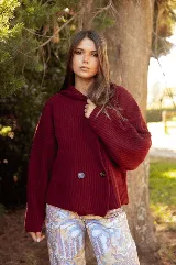 Saco de punto acanalado color bordó, con solapas anchas, cierre frontal cruzado con dos botones y mangas largas de corte holgado.