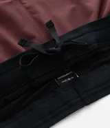 Bermuda deportiva color bordó con short interno de compresión negro integrado. Cuenta con cintura elástica con cordón de ajuste, bolsillos laterales con cierre y bolsillo interno. Confeccionada en tejido técnico de secado rápido.