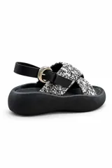 Sandalias de plataforma color negro, con tiras cruzadas de tela estampada en blanco y negro, tira trasera ajustable con hebilla metálica y suela chunky de goma.